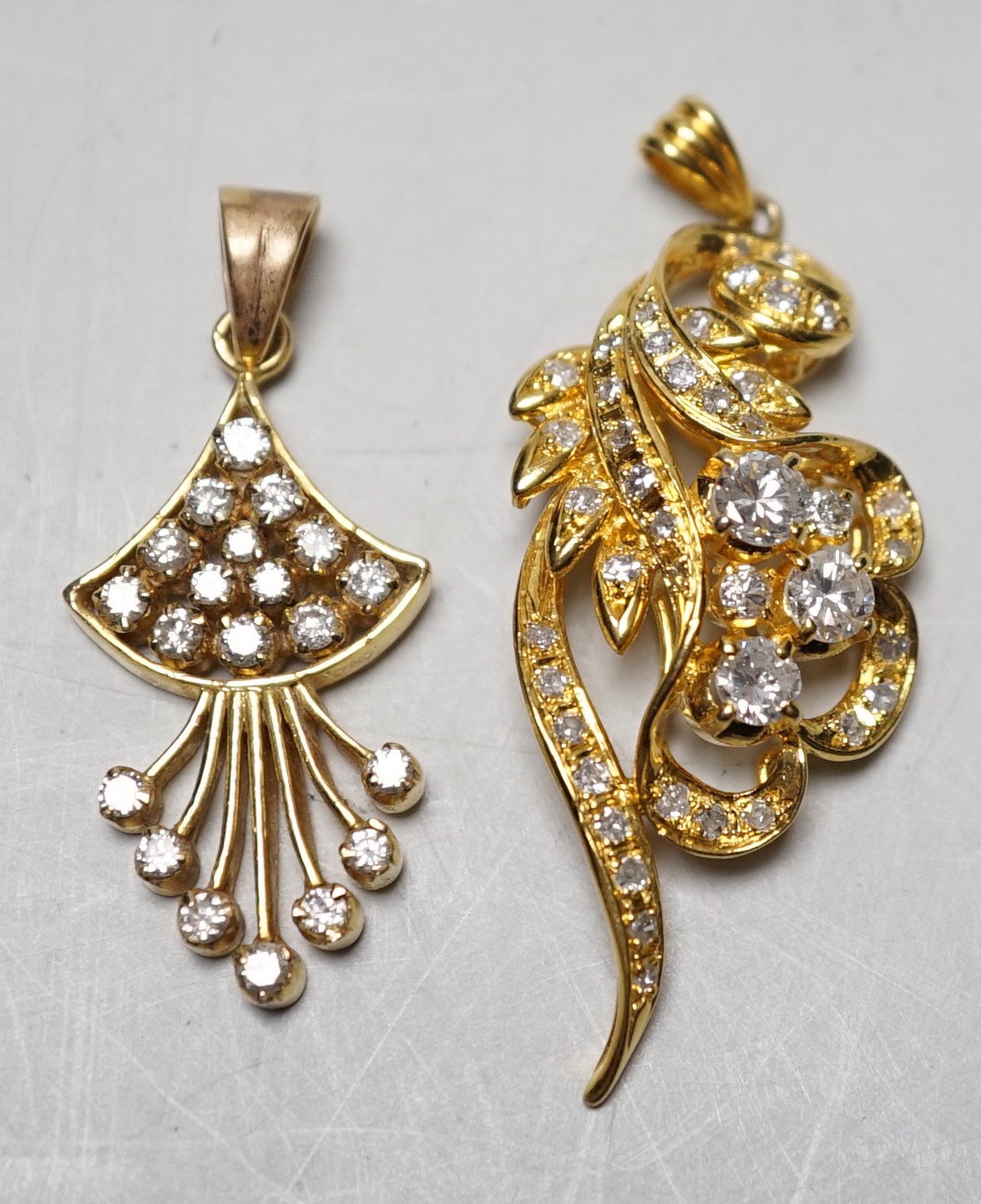 An Earl 18k yellow metal and diamond cluster ser scrolling pendant, overall 46mm and a yellow metal and diamond cluster set fan shaped pendant, gross weight 11.8 grams.